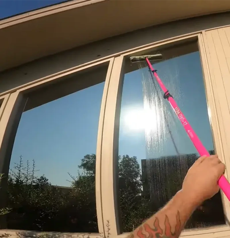 Cleaning a window with a water-fed pole and soft brush