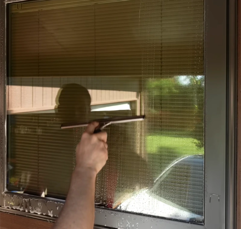 Pulling a squeegee across a window pane