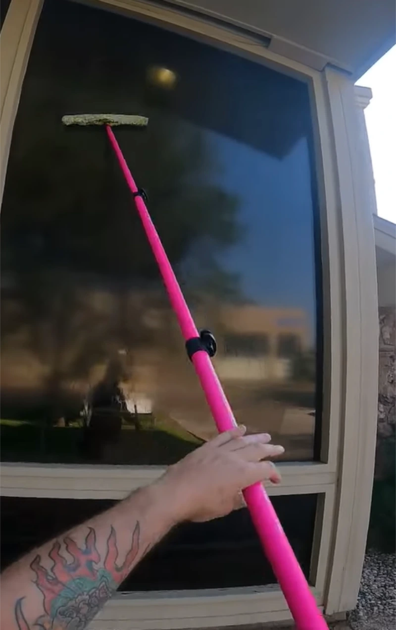 Window cleaner using a long pole on a tall window