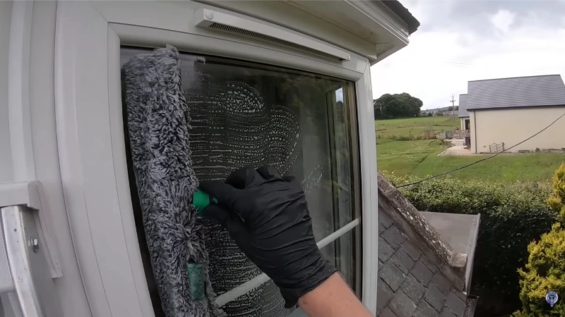 Gloved hand scrubbing a window frame