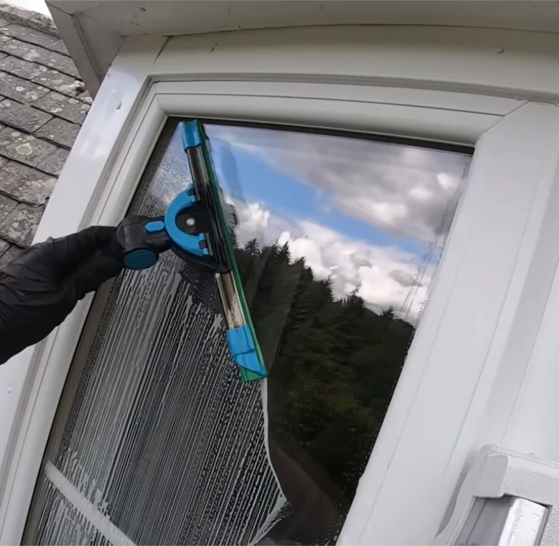 Gloved hand using a window cleaning tool on a window pane